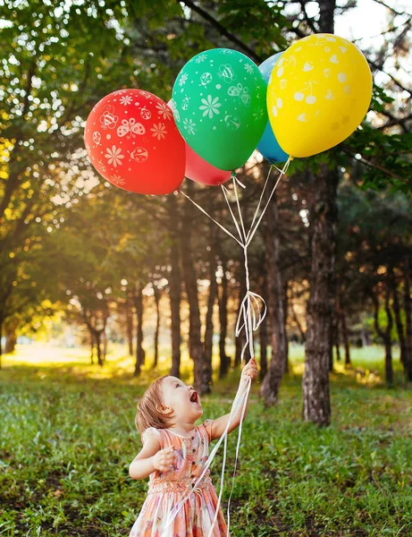 Baby girl 2-3 year old holding balloons outdoors. Birthday party. Childhood. Happiness — Stock Photo, Image