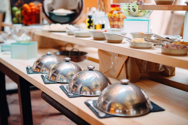 Buffet in een restaurant of hotel. Metalen schotels met dop. — Stockfoto