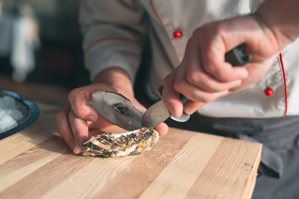 Öppnar de ihåliga och platta ostronen. Chef öppnar ostron i restaurangen. — Stockfoto