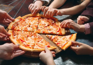 Ahşap masada Pizza dilimleri alarak eller, yakın görünüm.