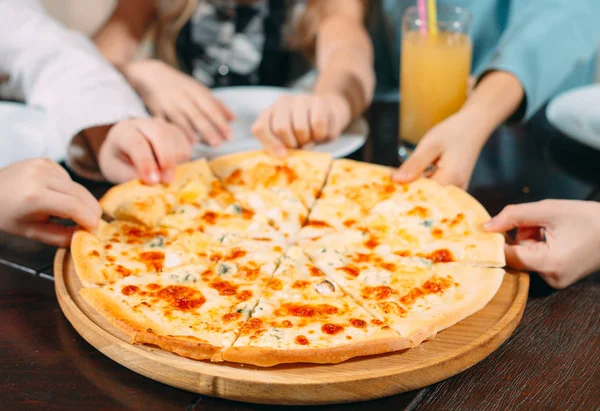 Hände nehmen Pizzascheiben vom Holztisch, Nahsicht — Stockfoto