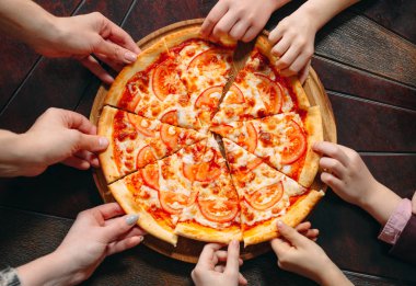 Ahşap masada Pizza dilimleri alarak eller, yakın görünüm.