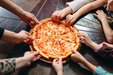 Ahşap masada Pizza dilimleri alarak eller, yakın görünüm.