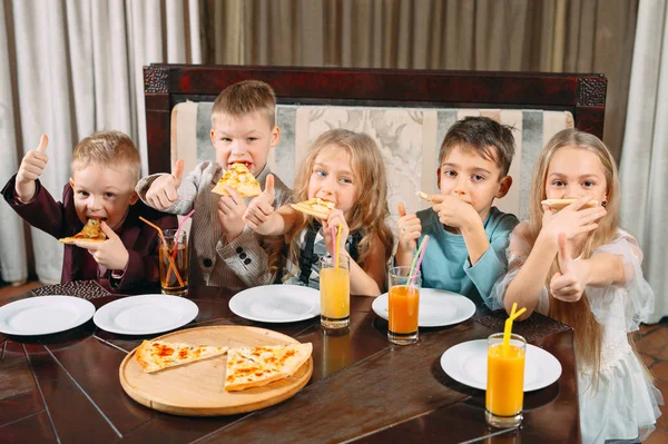 Lovely children eat pizza in the restaurant — Stock Photo, Image