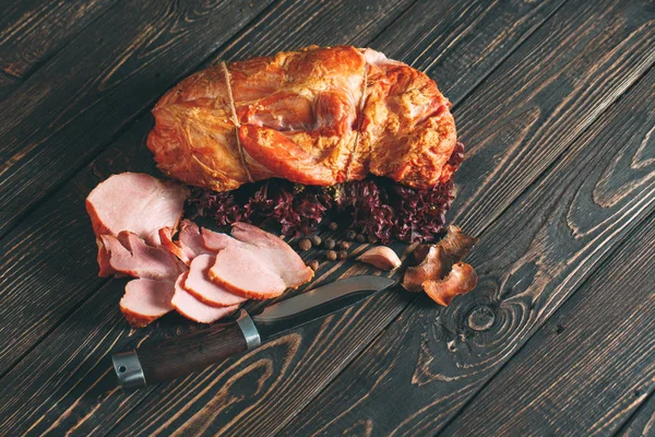 Tasty smoked meat on the wooden background.