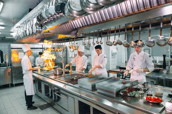 Moderne Küche. Köche bereiten die Mahlzeiten auf dem Herd in der Küche des Restaurants oder Hotels zu. Das Feuer in der Küche. — Stockfoto