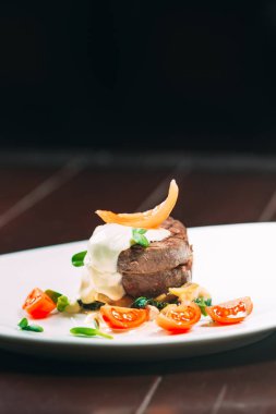 Ahşap bir arka plan üzerinde beyaz bir tabak üzerinde ıspanak ile dana madalyon