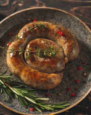 Tavada sarımsaklı kızarmış sosis. Karanlık tahtada..