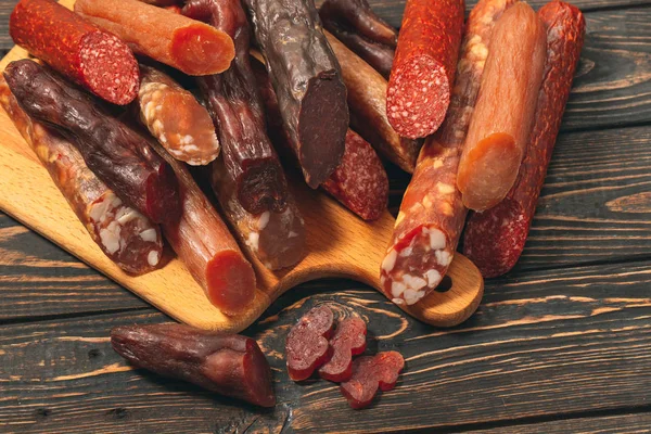 Diversi tipi di salsicce e prodotti a base di carne su una tavola di legno — Foto Stock