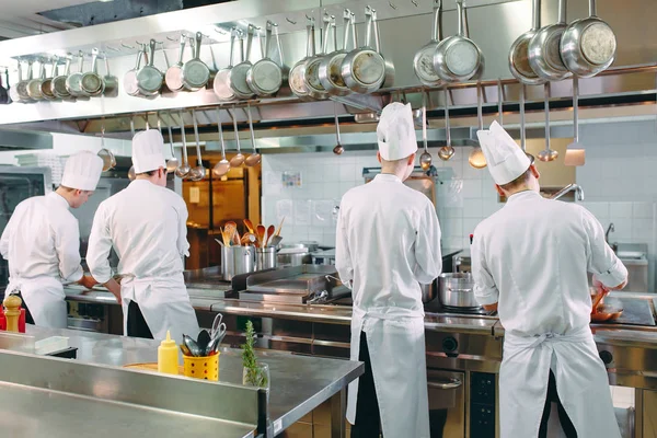 Cocina moderna. Los cocineros preparan comidas en la estufa en la cocina del restaurante u hotel. El fuego en la cocina. — Foto de Stock