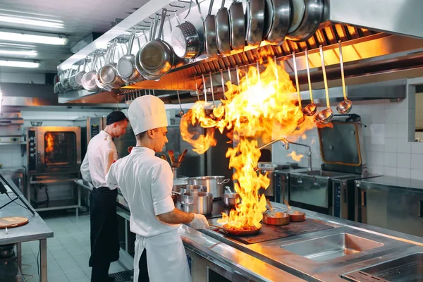 Moderne Küche. Köche bereiten die Mahlzeiten auf dem Herd in der Küche des Restaurants oder Hotels zu. Das Feuer in der Küche. — Stockfoto