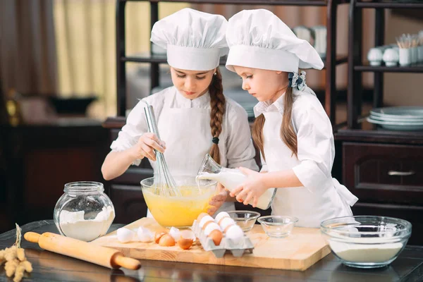 Meninas engraçadas crianças estão preparando a massa na cozinha . — Fotografia de Stock