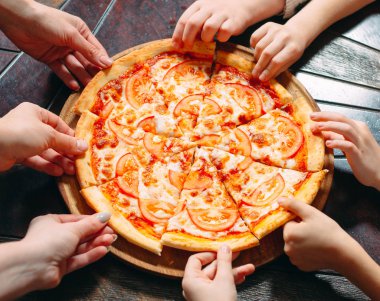 Ahşap masada Pizza dilimleri alarak eller, yakın görünüm.