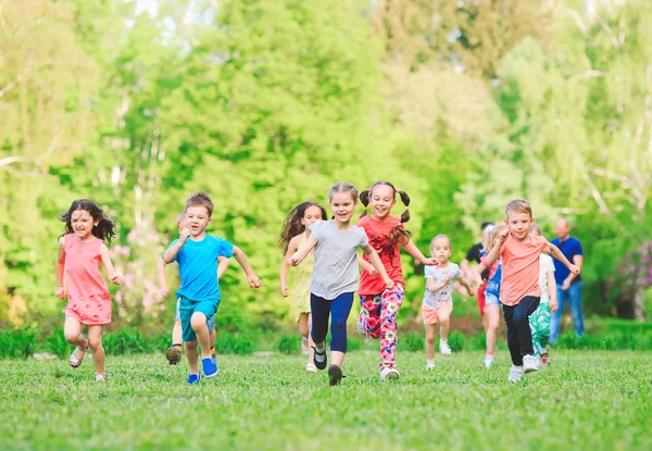 多くの異なる子供、男の子と女の子のカジュアルな服装で日当たりの良い夏の日、公園で走っています。. — ストック写真