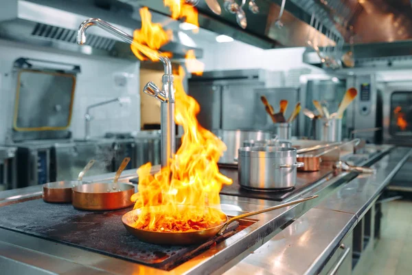 Cocina moderna. Los cocineros preparan comidas en la estufa en la cocina del restaurante u hotel. El fuego en la cocina. — Foto de Stock