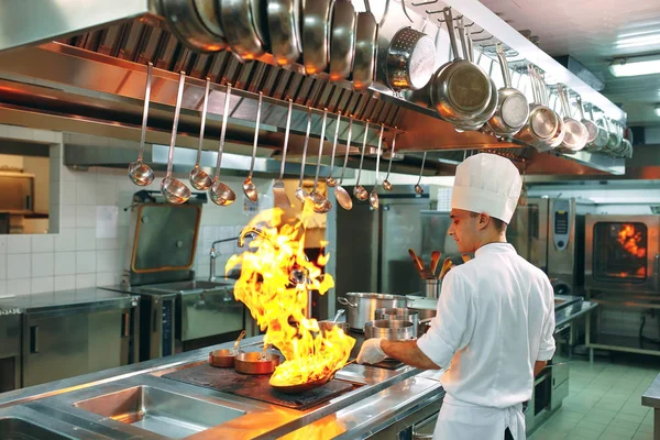 Modern konyha. A szakácsok az étterem vagy szálloda konyhájában, a kályhán készítenek ételeket. A tűz a konyhában.. — Stock Fotó