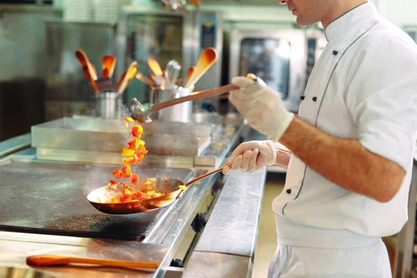 Chef cocinando verduras en sartén wok. Dof poco profundo. — Foto de Stock