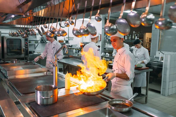 Cocina moderna. Los cocineros preparan comidas en la estufa en la cocina del restaurante u hotel. El fuego en la cocina. — Foto de Stock