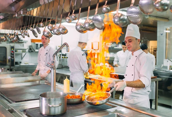 Современная кухня. Повара готовят блюда на плите на кухне ресторана или отеля. Пожар на кухне. — стоковое фото