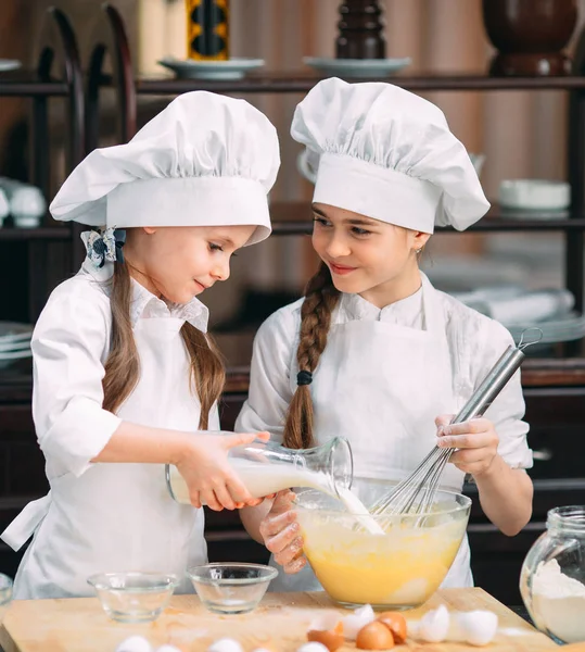 Meninas engraçadas crianças estão preparando a massa na cozinha . — Fotografia de Stock