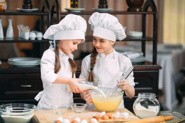 Meninas engraçadas crianças estão preparando a massa na cozinha . — Fotografia de Stock