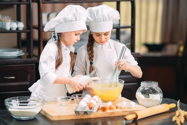 Meninas engraçadas crianças estão preparando a massa na cozinha . — Fotografia de Stock