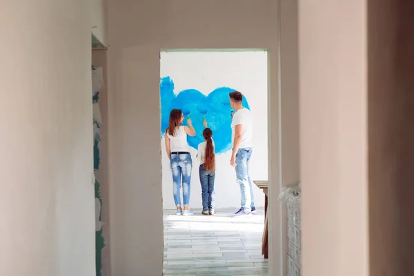 어머니, 아버지 및 어린 딸이 새로운 집에 있는 벽에 그림을 그리고 있다. — 스톡 사진