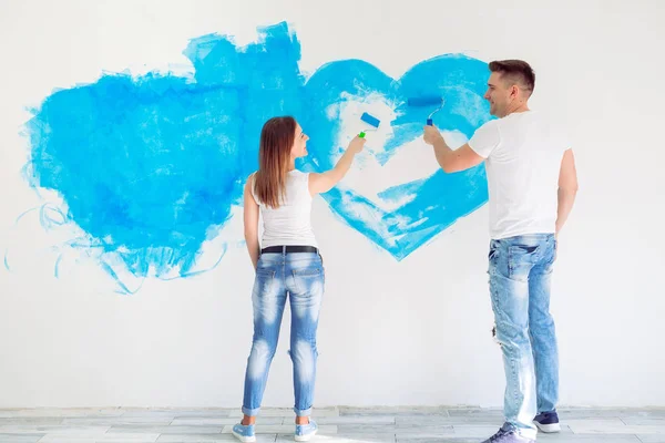 Pareja feliz pintando paredes en su nueva casa lista para vivir juntos. — Foto de Stock