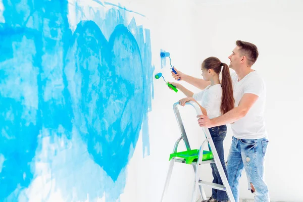 Father and his little daughter painting a wall in new home. — Stock Photo, Image