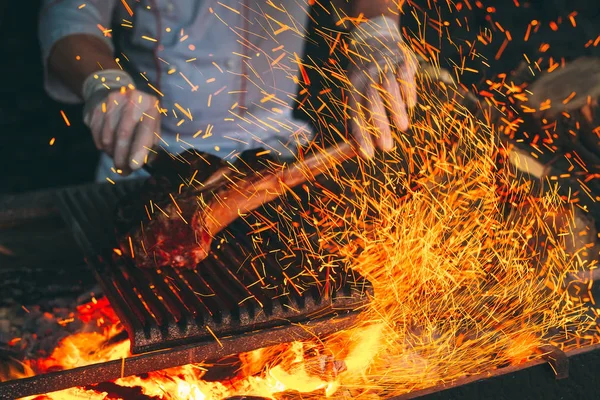 Šéfkuchař vaří steak. Kuchař zapálí maso v ohni. — Stock fotografie