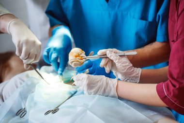 Cerrahi tiyatroda çalışan bir grup cerrah. Sağlık ekibi çelik tıbbi aletler taşıyan koruyucu maskeler takıyor.