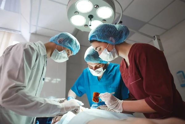 Grupo de cirurgiões a trabalhar no teatro cirúrgico. Equipe de medicina de ressuscitação usando máscaras protetoras segurando ferramentas médicas de aço — Fotografia de Stock