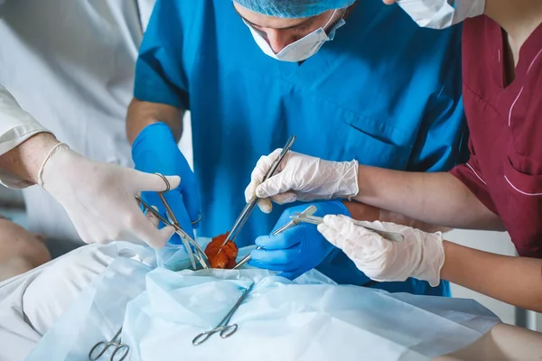 Groupe de chirurgiens au travail opérant en salle d'opération. Équipe de médecine de réanimation portant des masques de protection tenant des outils médicaux en acier — Photo