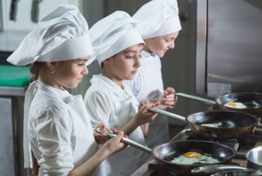 Çocuklar restoranın mutfağında yumurta pişiriyor..