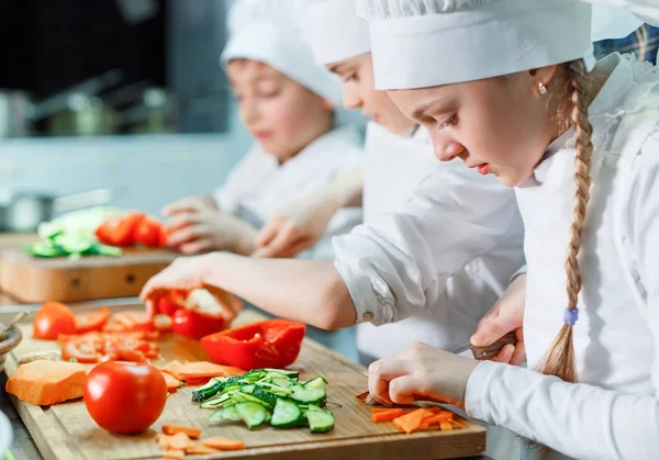 Niños en chefs sombrero moler verduras en la cocina . — Foto de Stock