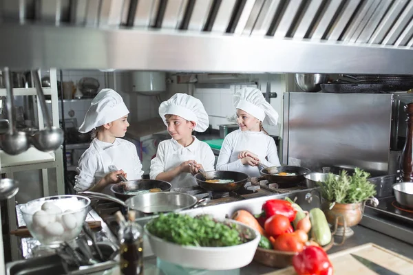 Los niños cocinan huevos en la cocina del restaurante. — Foto de Stock