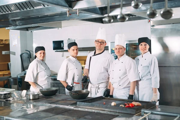 Cinque chef che indossano uniformi in posa in cucina. — Foto Stock