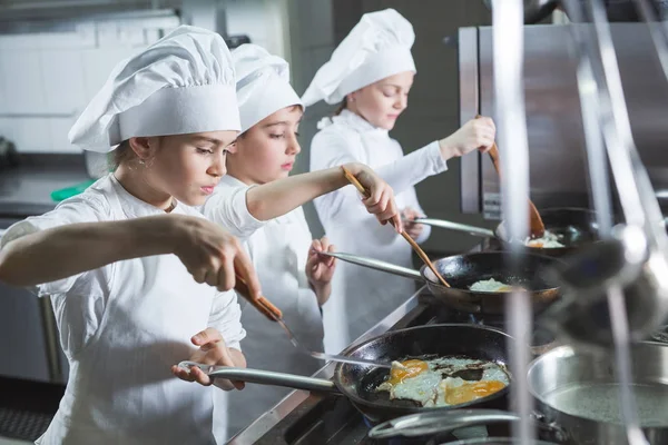 Los niños cocinan huevos en la cocina del restaurante. — Foto de Stock