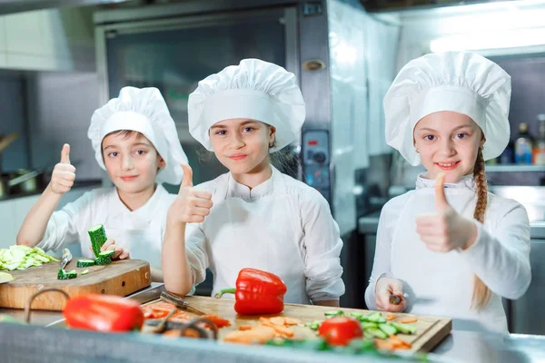 Niños en chefs sombrero moler verduras en la cocina . — Foto de Stock