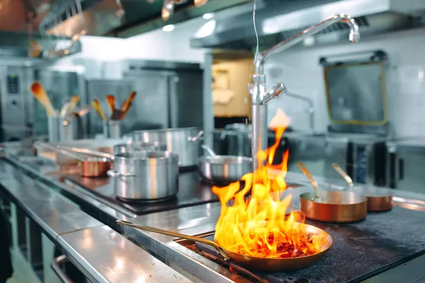 Modernt kök. Matlagare lagar mat på spisen i köket i restaurangen eller hotellet. Branden i köket. — Stockfoto