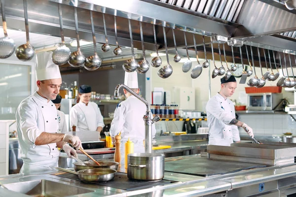 Modern konyha. A szakácsok az étterem vagy szálloda konyhájában, a kályhán készítenek ételeket. A tűz a konyhában.. — Stock Fotó