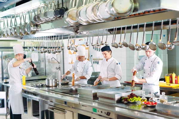 Modernt kök. Matlagare lagar mat på spisen i köket i restaurangen eller hotellet. Branden i köket. — Stockfoto