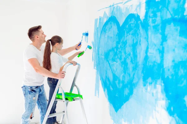 Father and his little daughter painting a wall in new home. — Stock Photo, Image