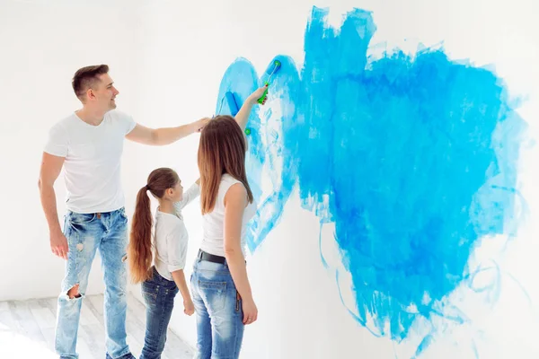 Madre, padre e hija pintando la pared en su nuevo hogar. — Foto de Stock