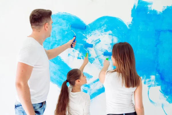 Madre, padre e hija pintando la pared en su nuevo hogar. — Foto de Stock