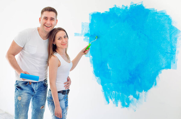 Happy couple painting walls in their new house ready for living together.