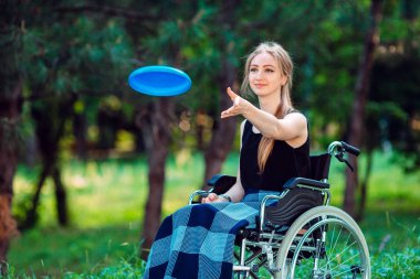 Genç engelli bir kız küçük kız kardeşiyle frizbi oynuyor. Sağlıklı bir insanın engelli biriyle etkileşimi