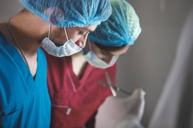 Cerrahi tiyatroda ameliyat eden bir grup cerrah iş başında. Koruyucu maske takan resüsitasyon tıp ekibi