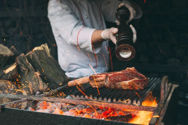 Chef poivre le steak sur un feu. — Photo
