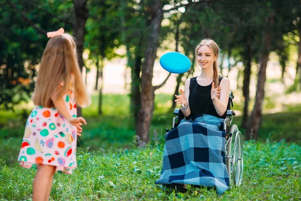 Une jeune fille handicapée joue au frisbee avec sa sœur cadette. Interaction d'une personne en bonne santé avec une personne handicapée — Photo